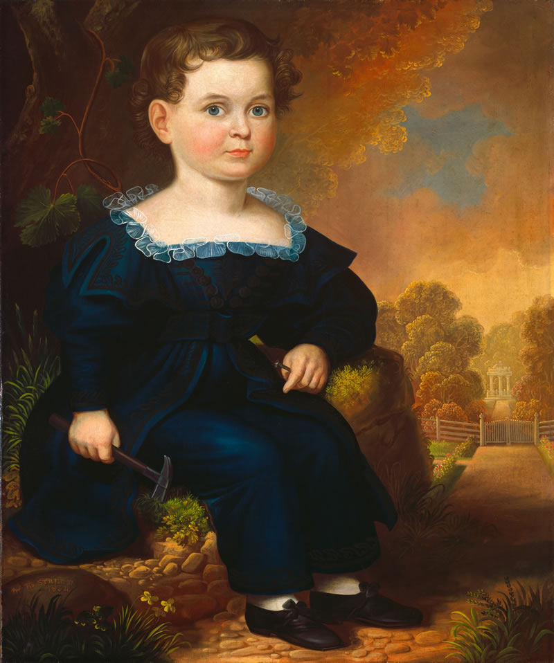 Portrait of a young boy in a blue dress sitting outdoors with a landscape background