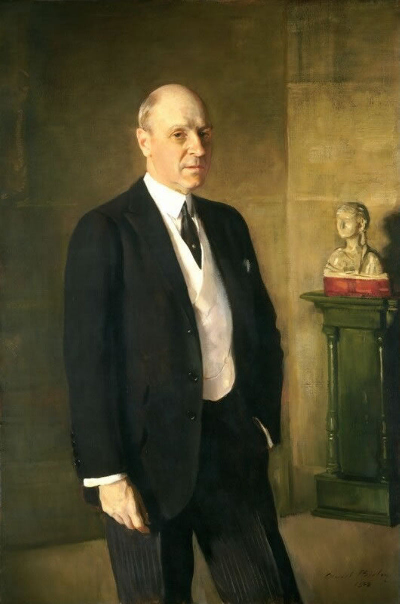 Man in a suit standing in front of a wall with a bust on a pedestal