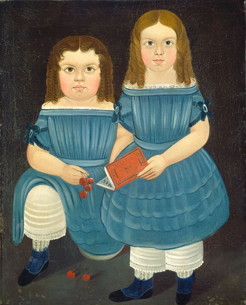 Two young girls in blue dresses holding a book and berries on a dark background