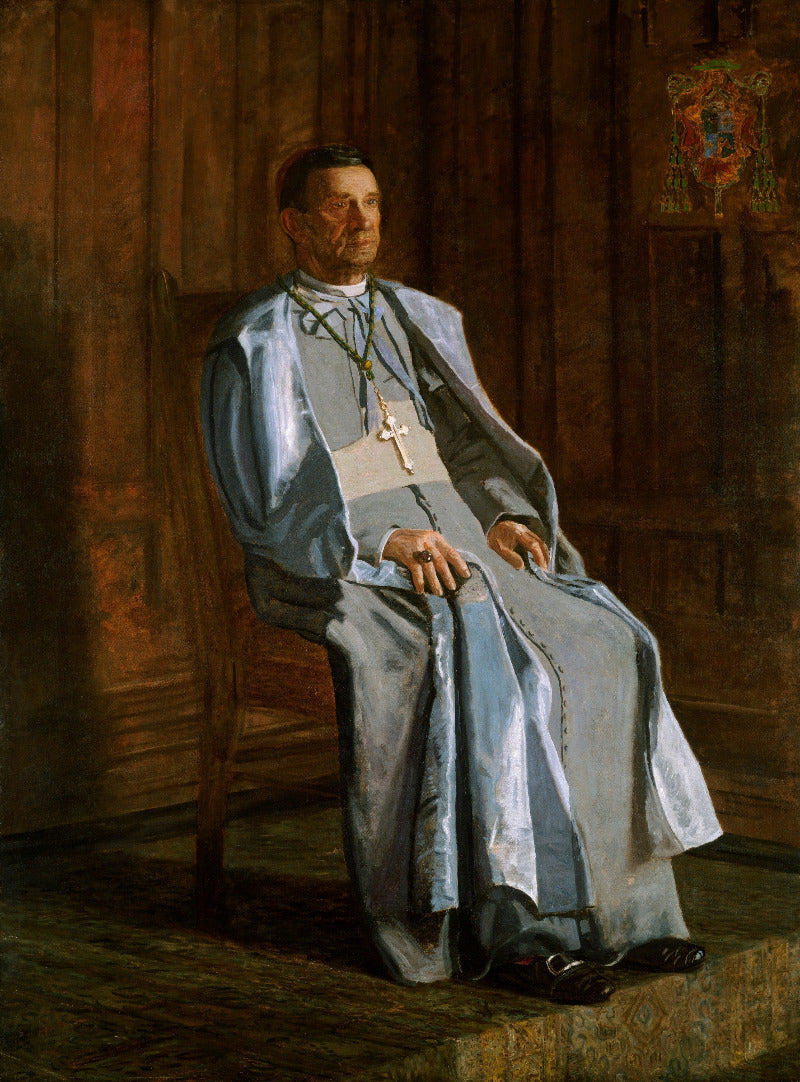 Portrait of a man in religious attire sitting in a dimly lit room.