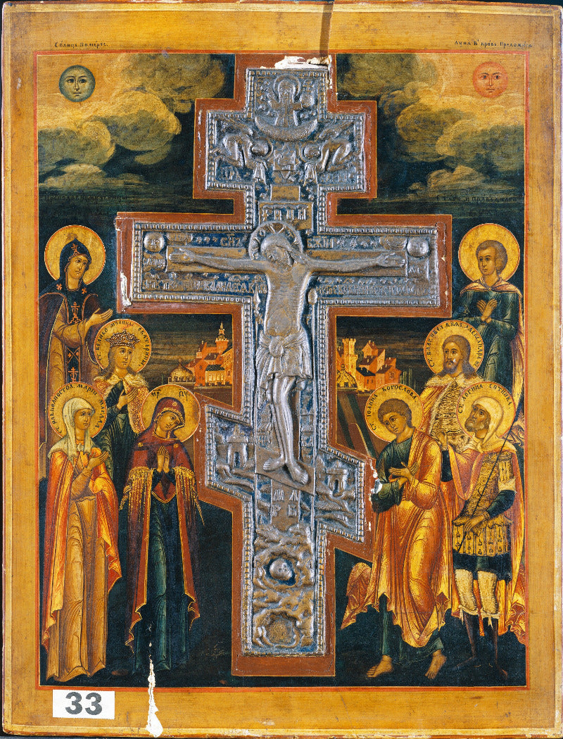 An ornate religious icon painting featuring a large central silver-toned crucifix with a raised figure of Jesus, surrounded by haloed saints and angels in gold, red, blue, and brown tones against a dark sky background.