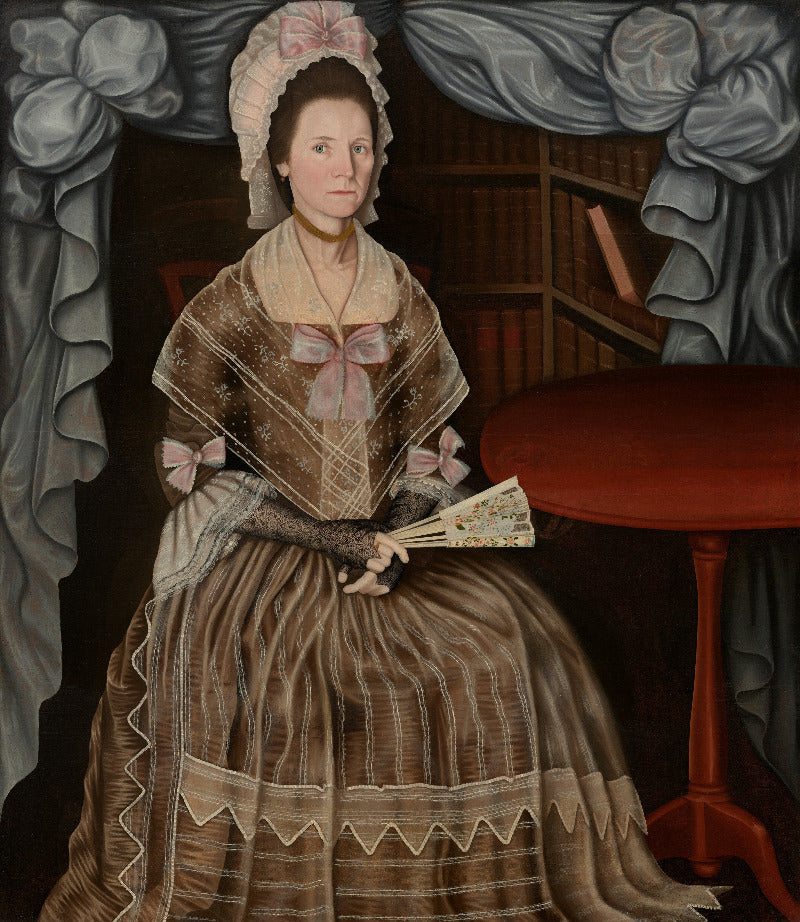 A historical portrait painting of a woman seated indoors, wearing a brown and beige dress with pink bows and a white bonnet, holding a folding fan. She is framed by gray drapery, with a red table on the right and dark bookshelves behind her.