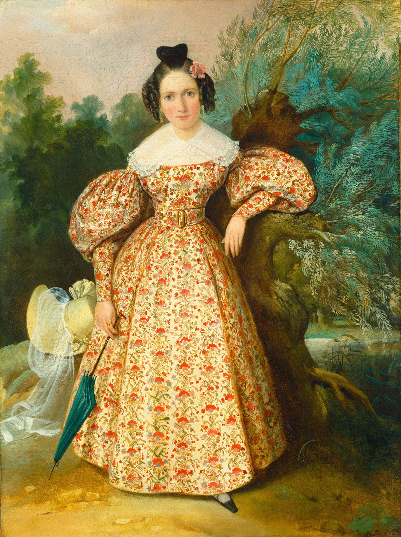 Portrait of a woman in a floral dress standing outdoors with trees and a landscape in the background.